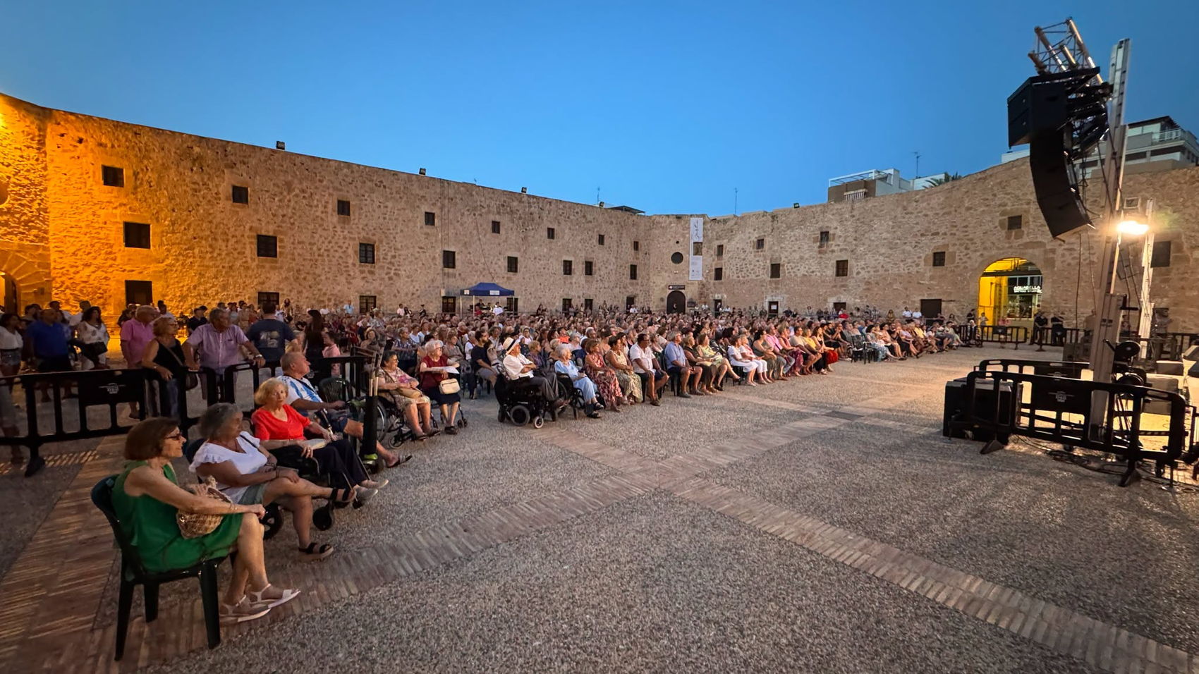 El público llenando el patio del castillo al atardecer